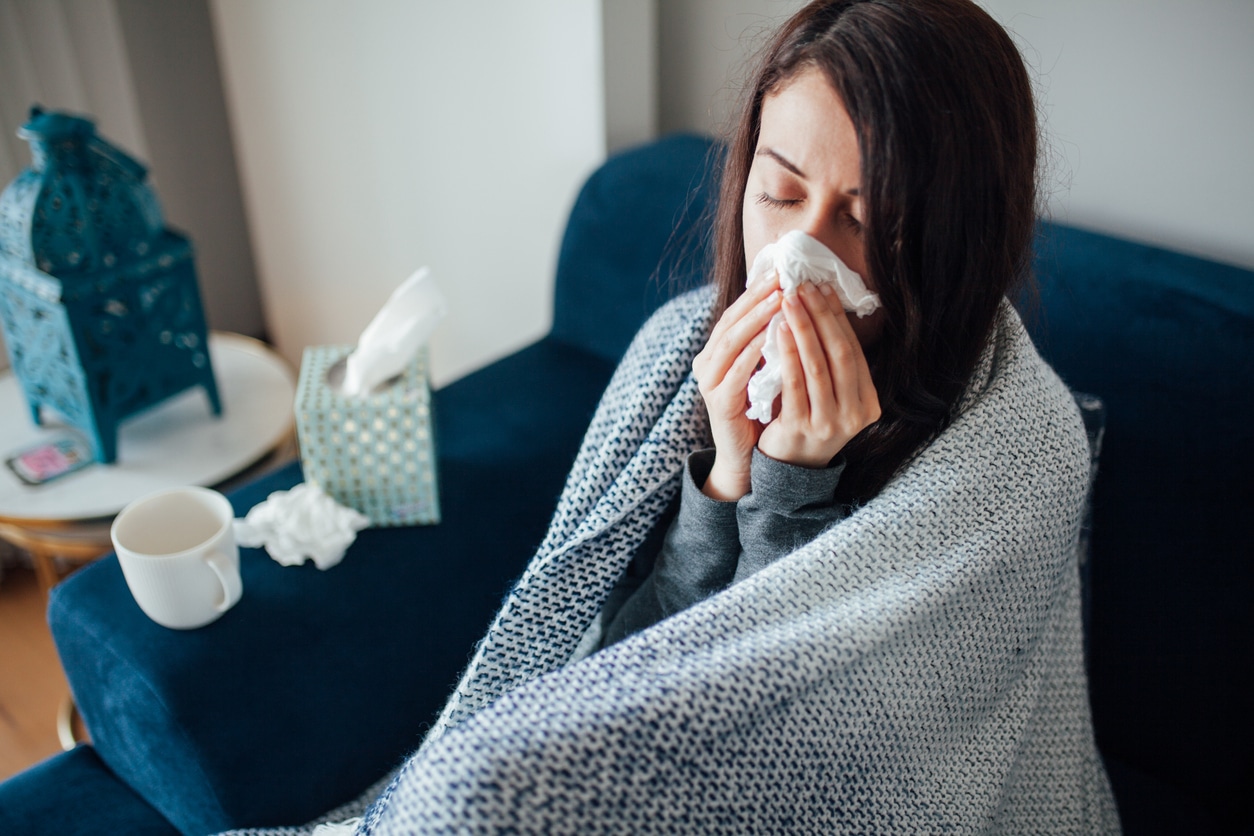 Femme malade soufflant son nez, elle couvrait avec la couverture