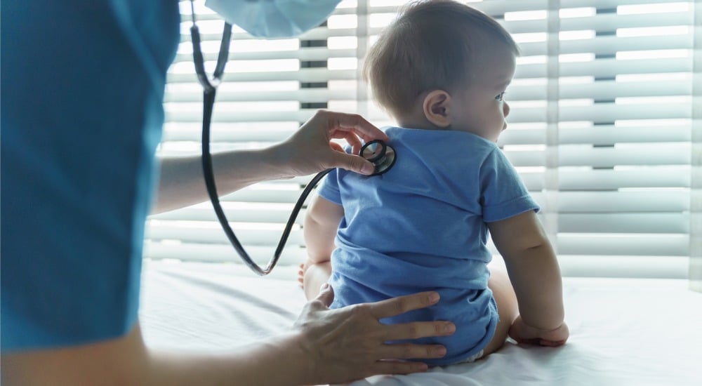 Médecin pédiatre féminin asiatique examinant son petit bébé patient avec stéthoscope dans la chambre médicale