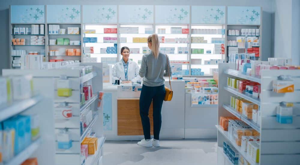 jeune femme au comptoir d'une pharmacie, aide aux pharmacies fragiles