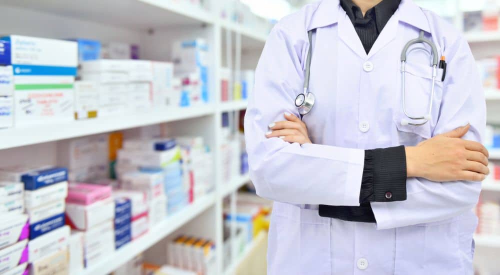 Pharmacien les bras croisés dans son officine