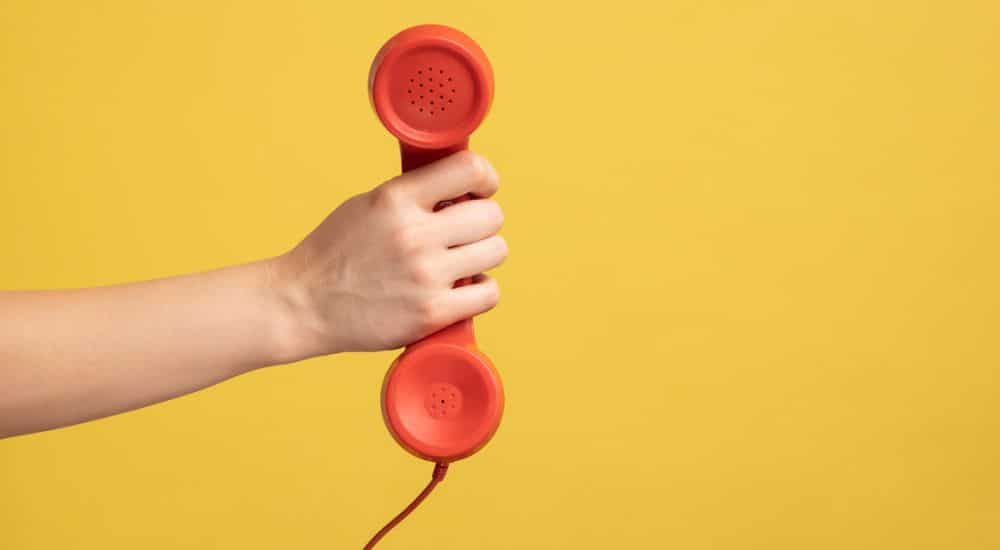 gros plan de la main d’une femme tenant et montrant le récepteur du combiné téléphonique, ligne relais ANEPF