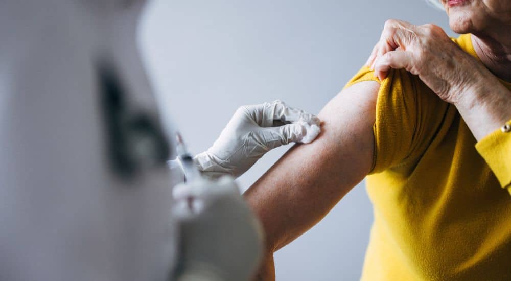 Femme âgée vaccinée par un professionnel de santé avec des gants de protection