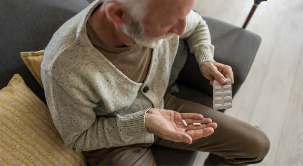Homme âgé prenant des médicaments dans sa main. Antalgique palier I